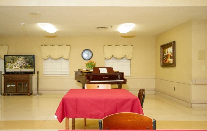 A simple room with a piano and a table covered with a red tablecloth.