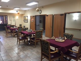A cozy dining area with neatly arranged tables and chairs, featuring soft lighting and warm decor.