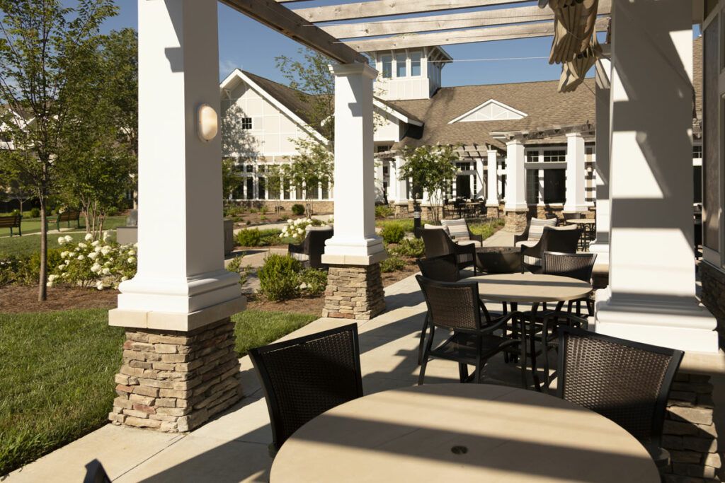 A sunny outdoor patio area with tables, chairs, and a pergola at a restaurant.