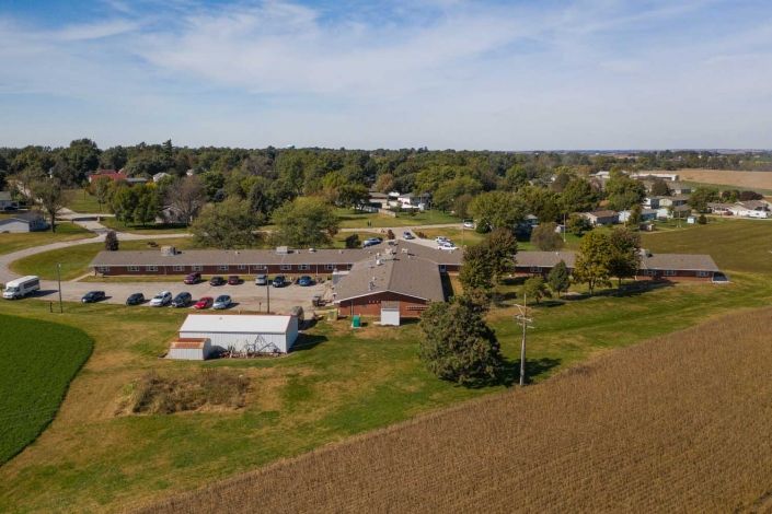 Aerial view of a rural landscape featuring buildings, farmland, and lush greenery.