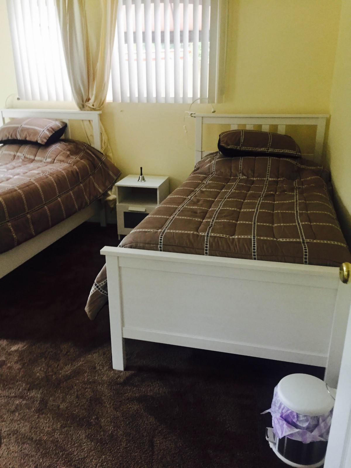 A cozy bedroom with two single beds and a small side table.