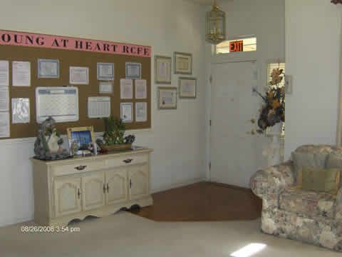 A cozy living room with a bulletin board, decorative furniture, and plants near the entryway.