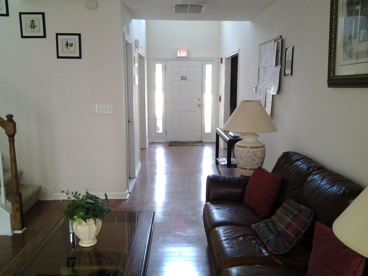 A cozy living room with a view down a hallway towards the front door.