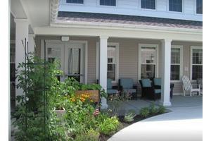 A cozy porch with outdoor seating and a surrounding garden.