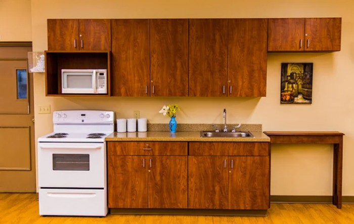 A well-organized kitchen featuring wooden cabinets, a white oven and microwave, and a small countertop with a sink.