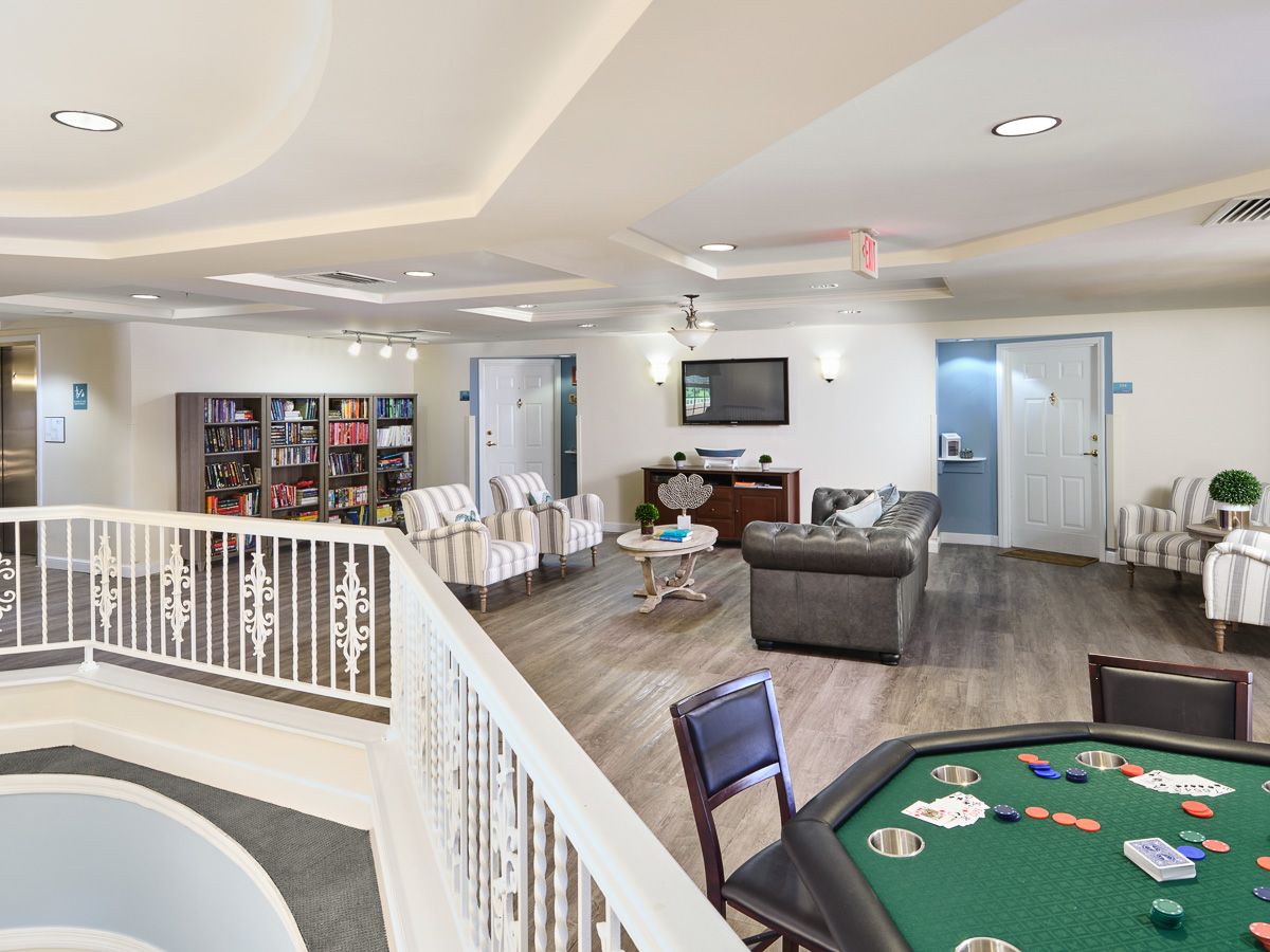 A spacious and modern entertainment room with a seating area and a poker table.
