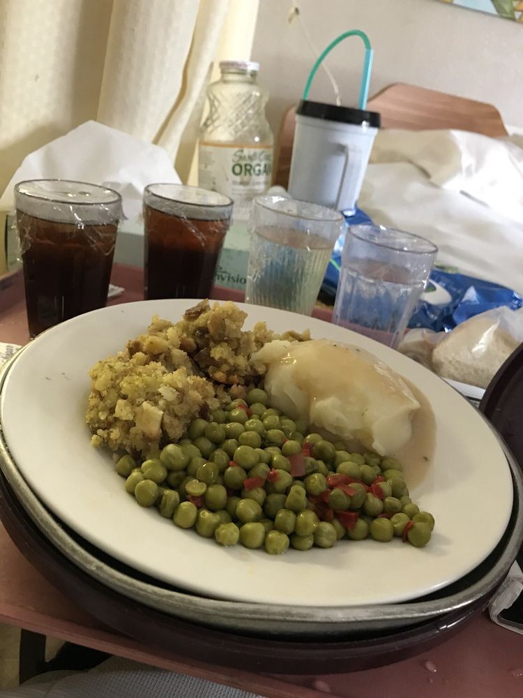 A meal consisting of chicken, peas, and stuffing served on a plate with drinks in the background.