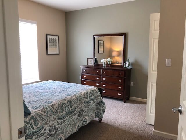 A cozy bedroom with a bed, dresser, and mirror.
