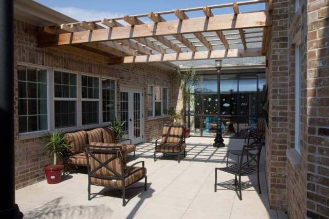 A sunny patio featuring a pergola with outdoor seating and a table.
