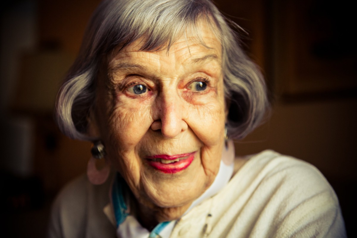 A smiling elderly woman in a close-up portrait indoors.