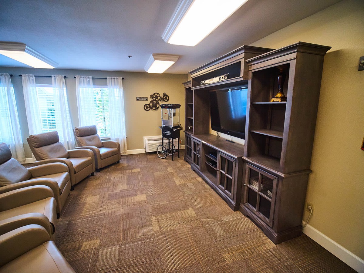 A cozy living room with armchairs and an entertainment center featuring a large TV.