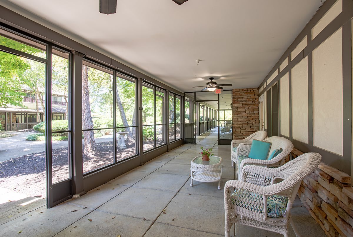 A cozy screened porch with wicker furniture and a ceiling fan, offering a relaxing outdoor space.