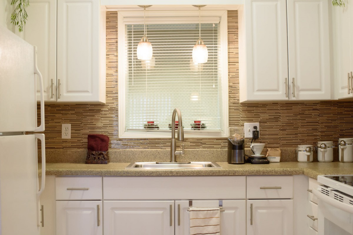 Modern kitchen interior with white cabinets and a central sink.