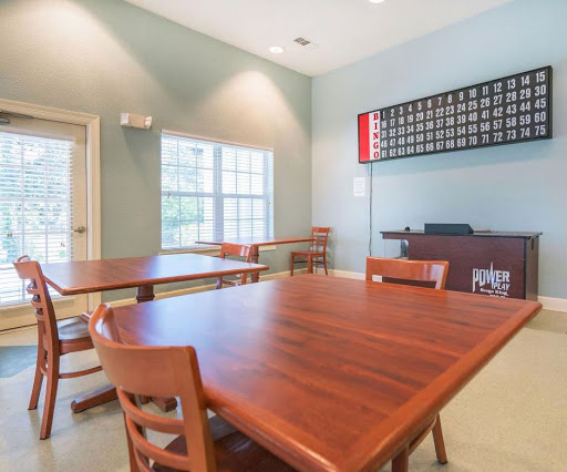 A well-lit community room featuring wooden tables and chairs, perfect for gatherings or meetings.