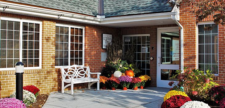 A welcoming entrance with a decorative bench and vibrant autumn flowers.