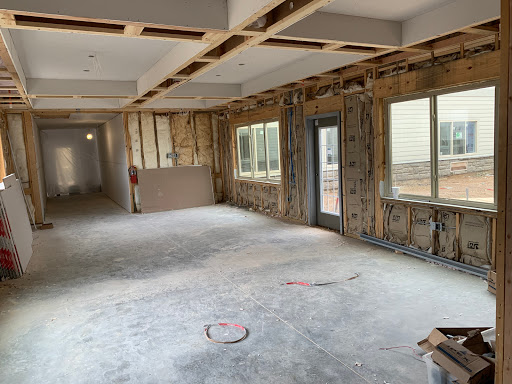 An interior space under renovation, showcasing exposed walls and construction materials.