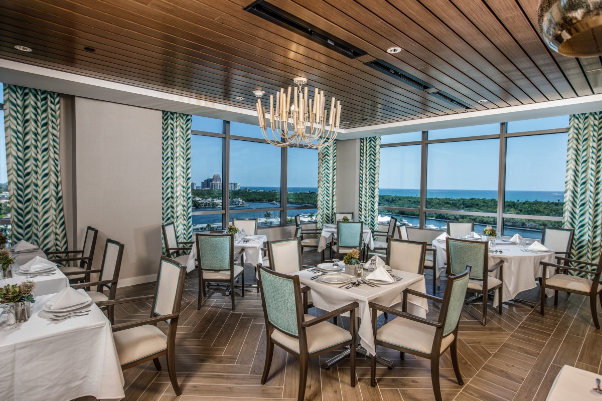 An elegant restaurant dining room with a view of the ocean through large windows.