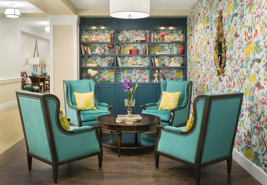 A cozy living room with turquoise armchairs and a vibrant bookshelf.