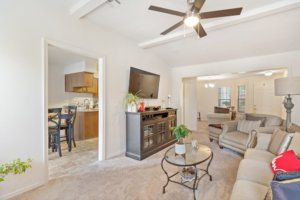 A cozy living room with modern furnishings, featuring a ceiling fan, television, and comfortable seating.