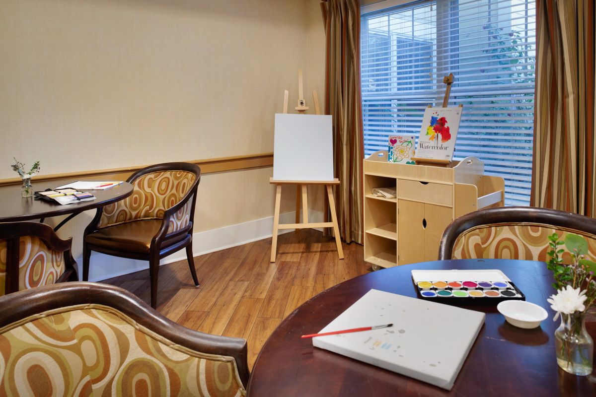 An art room with an easel, drawing supplies, and comfortable seating.