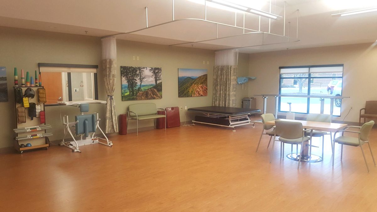 A spacious room featuring paintings on the wall, furniture, and ample lighting.