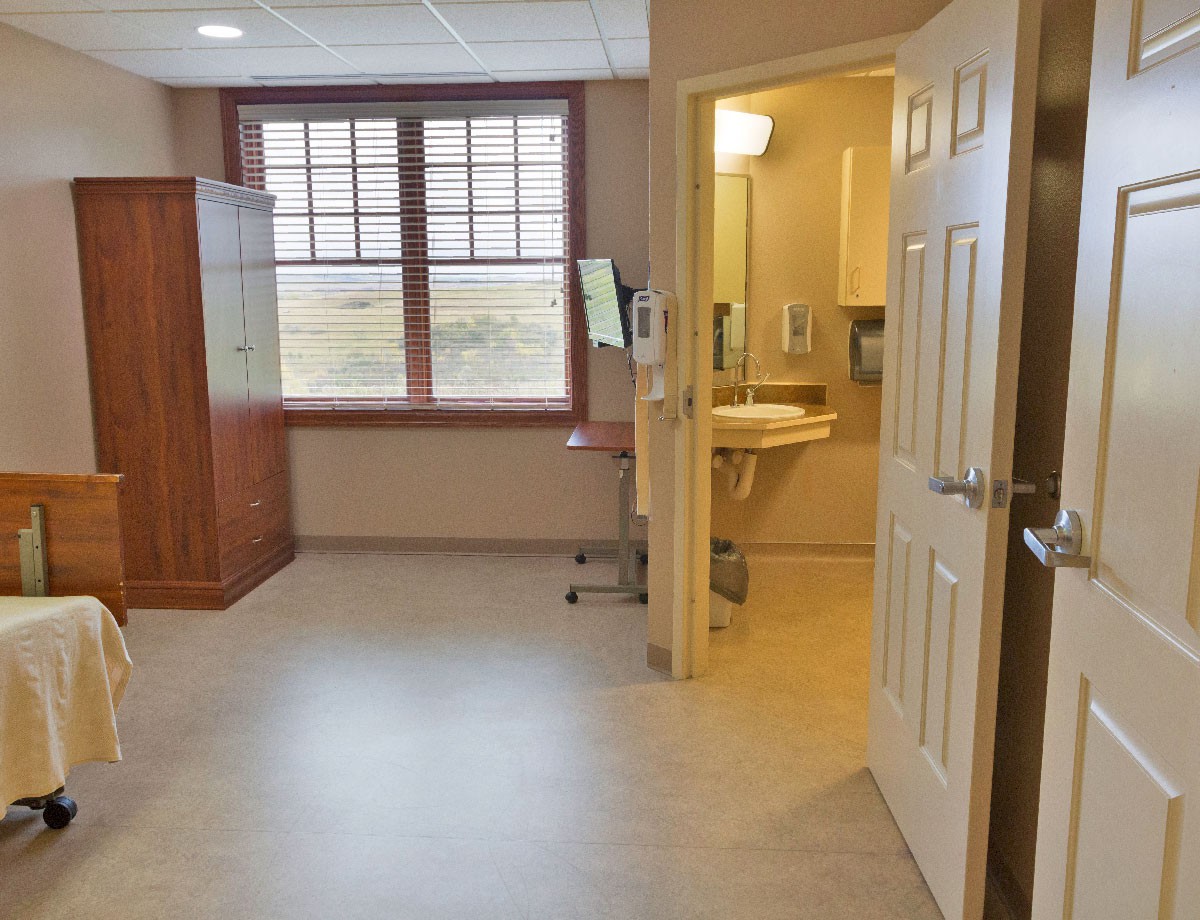A clean and empty hospital patient room with an adjoining bathroom.