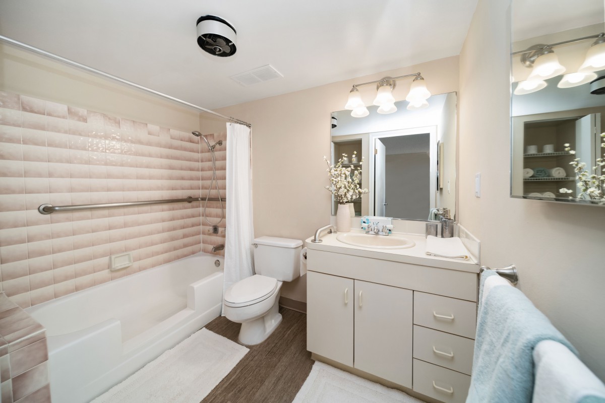 A clean and modern bathroom with a vanity, sink, toilet, and bathtub with a shower curtain.