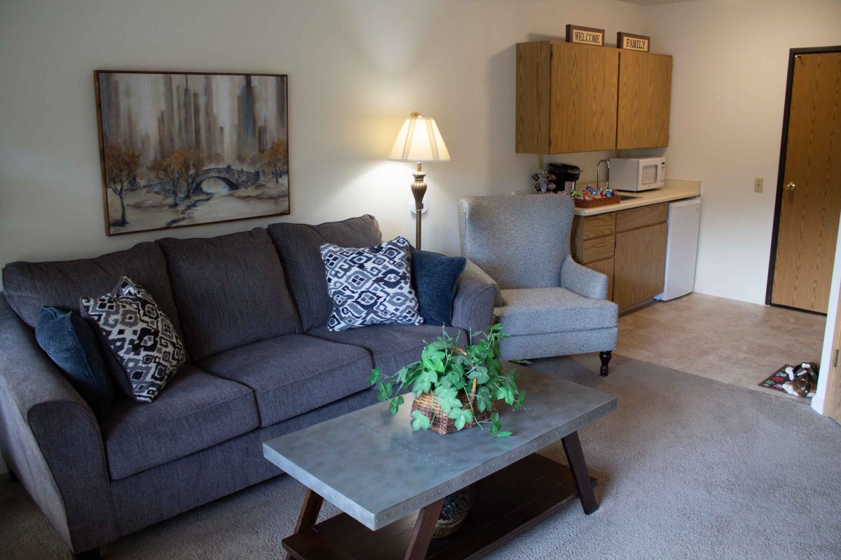 A cozy living room with a sofa, armchair, coffee table, and a lamp.