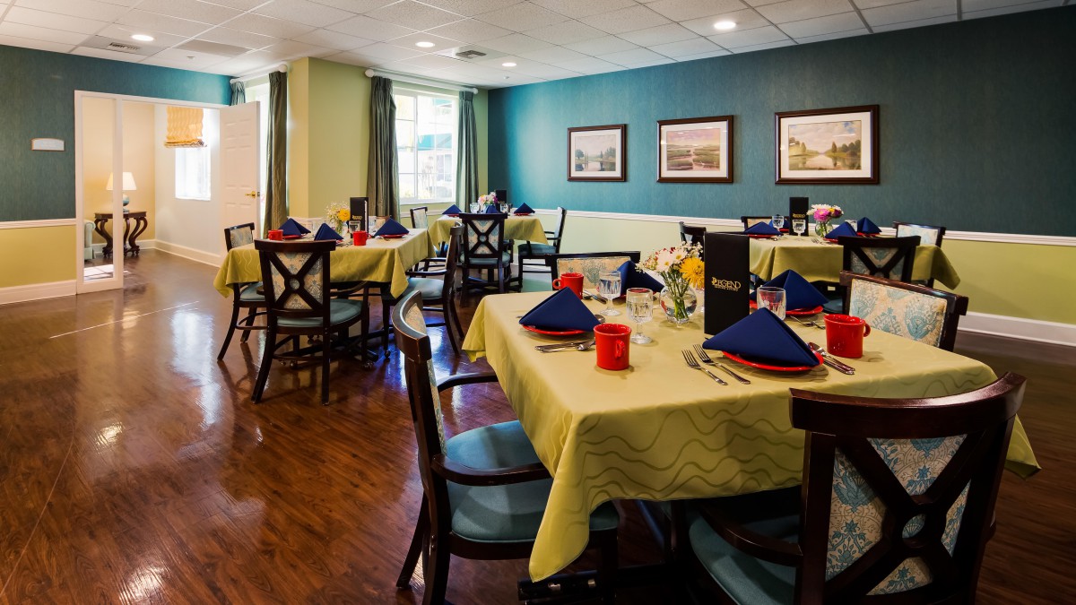 An elegantly set dining room with neatly arranged tables and chairs, featuring colorful napkins and tasteful decor.