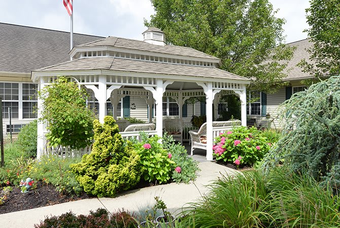 A charming gazebo surrounded by a beautifully landscaped garden with vibrant flowers and greenery.