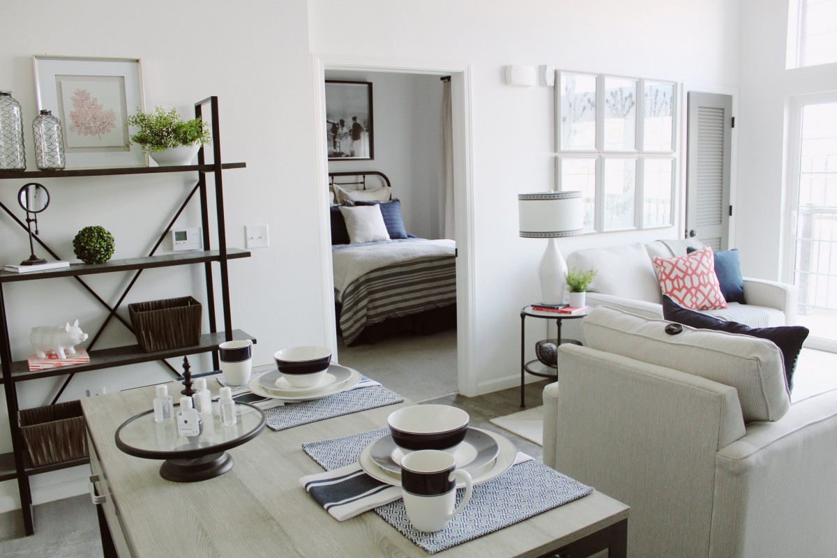 A modern open-concept living space featuring a dining area and view into a cozy bedroom.