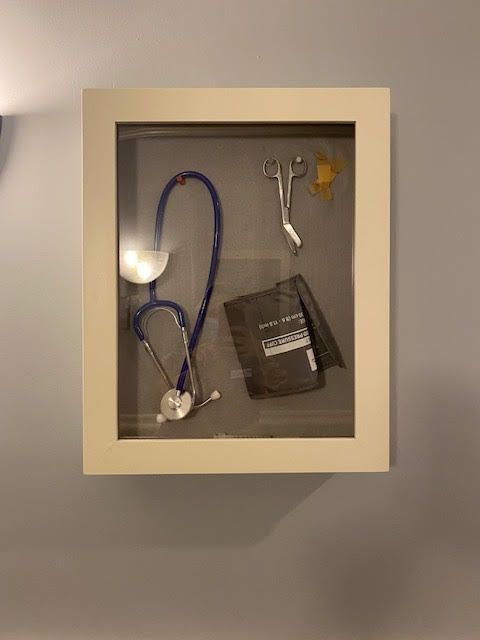 A shadow box displaying a stethoscope and blood pressure cuff.