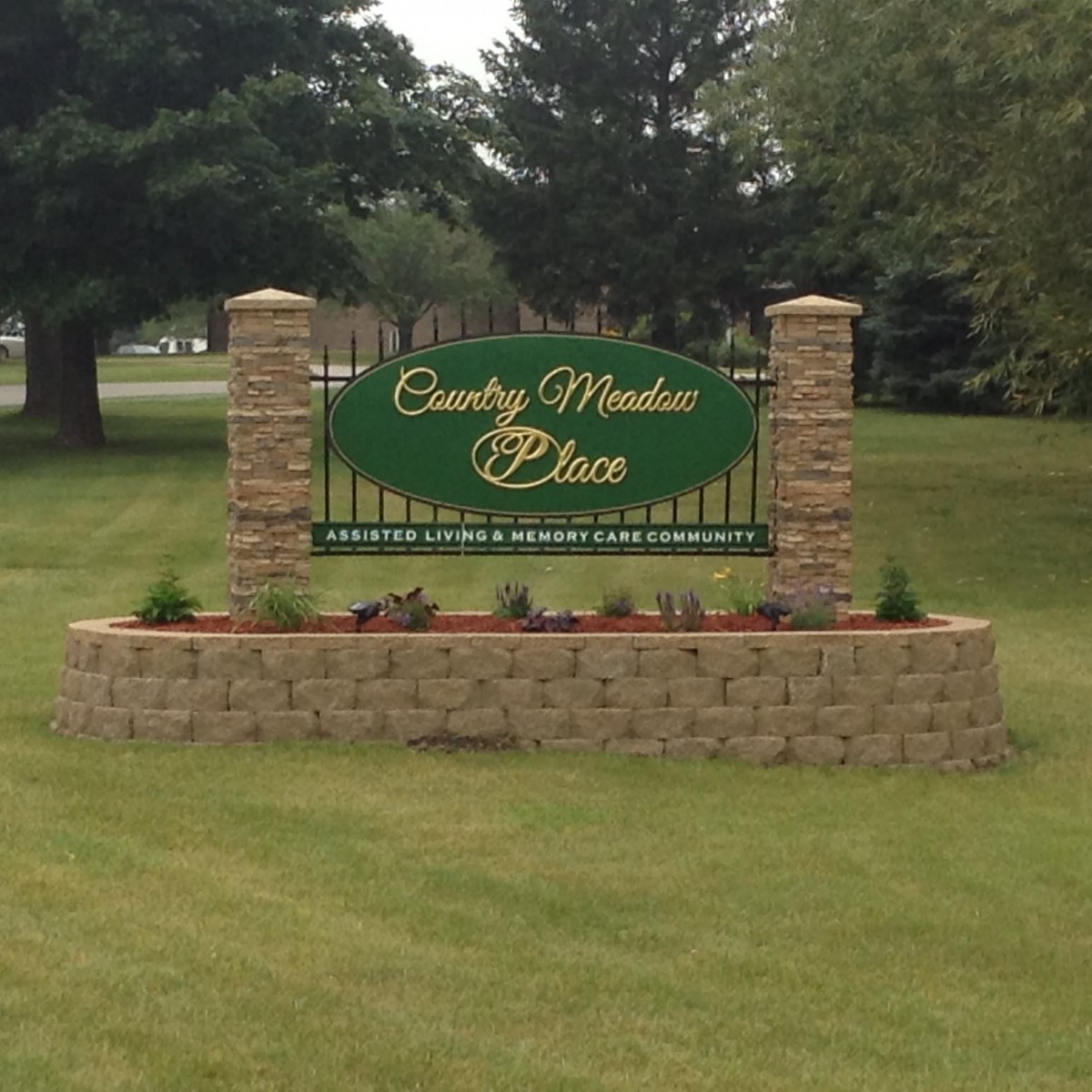 A landscaped area with a sign reading 'County Meadow Place' surrounded by greenery.