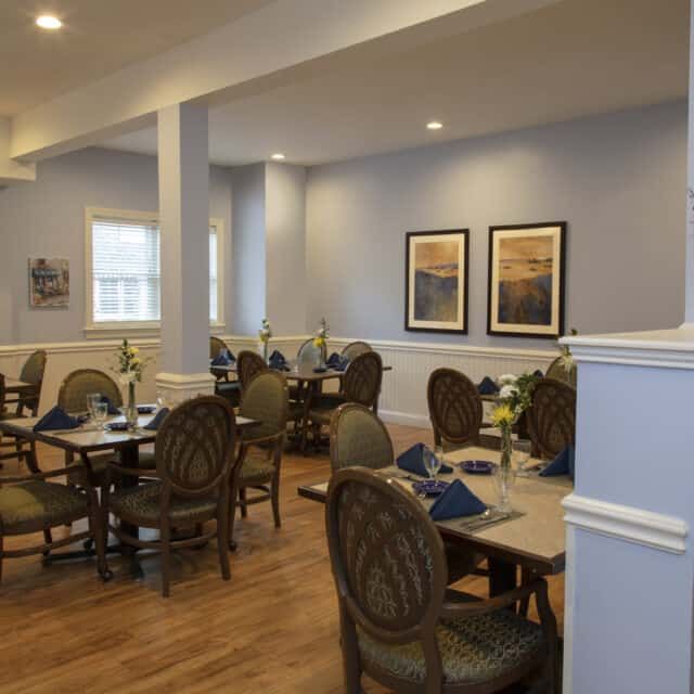 A cozy dining area with neatly arranged tables and chairs, adorned with artwork on the walls.