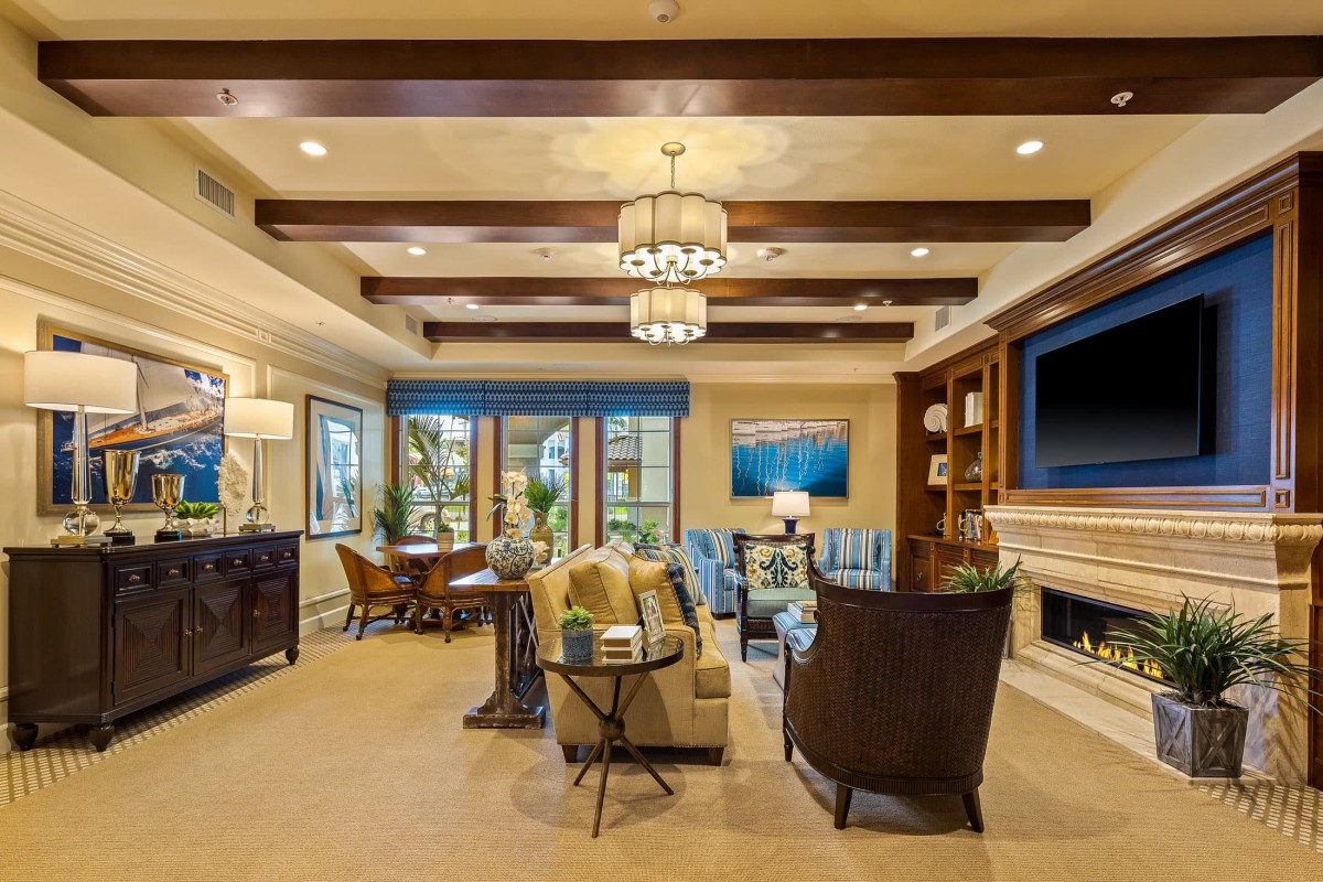 A modern living room with elegant decor, featuring ceiling beams, a fireplace, and stylish furniture.