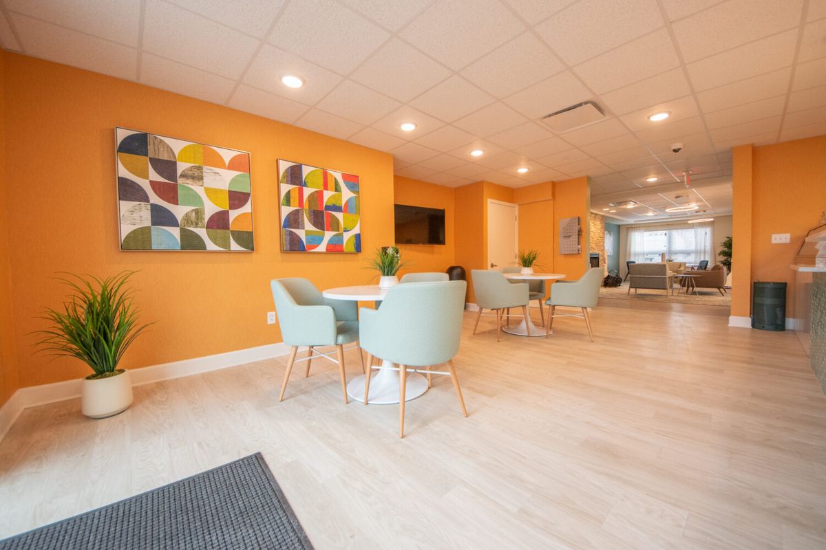 A modern lobby with orange walls, decorated with abstract art and featuring a stylish seating area.
