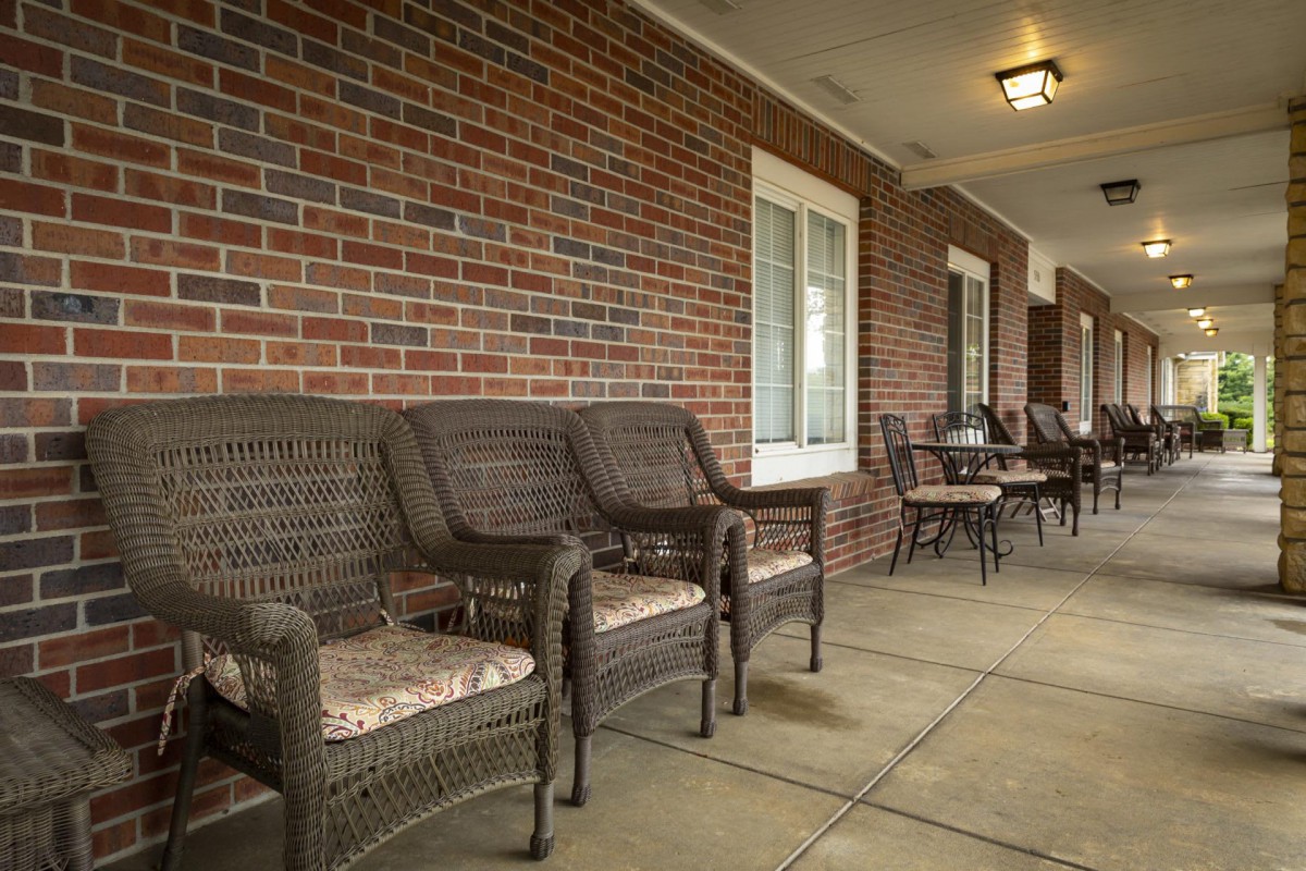 A cozy porch with wicker furniture against a brick wall.