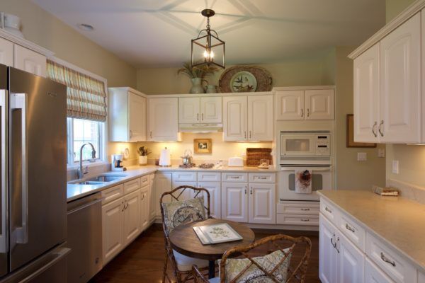 A cozy kitchen with white cabinets and a small dining table under modern lighting.