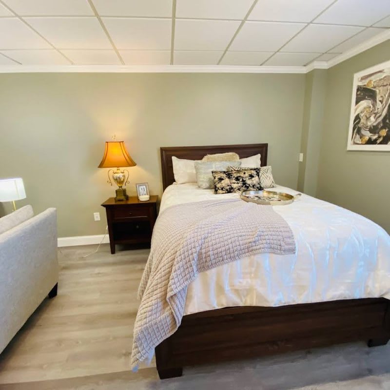 A cozy bedroom with a neatly made bed, bedside lamp, and modern decor.