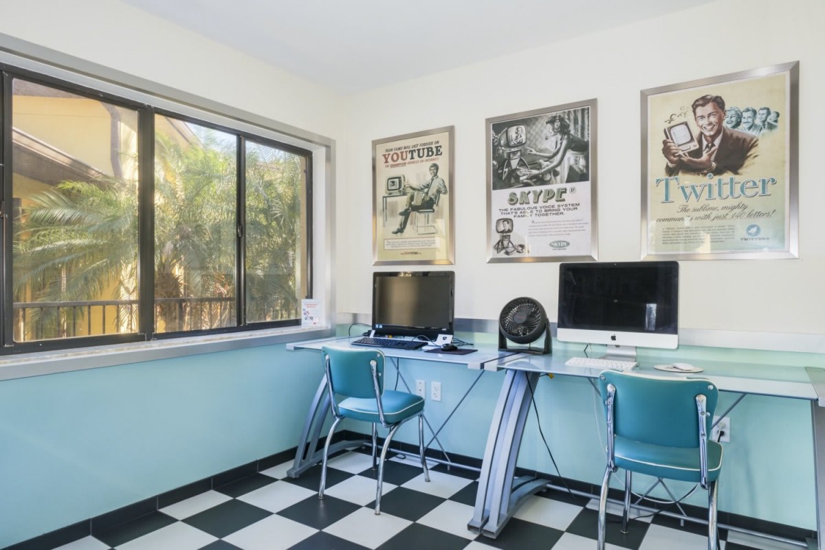 A retro-themed home office with vintage posters, blue chairs, and checkered flooring.