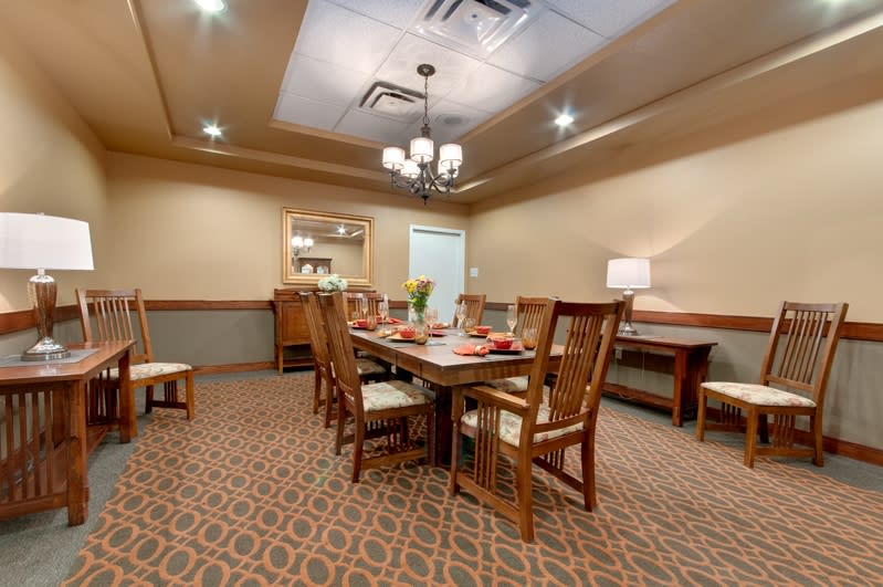 A well-lit dining room with a central table and chairs, featuring elegant interior decor.