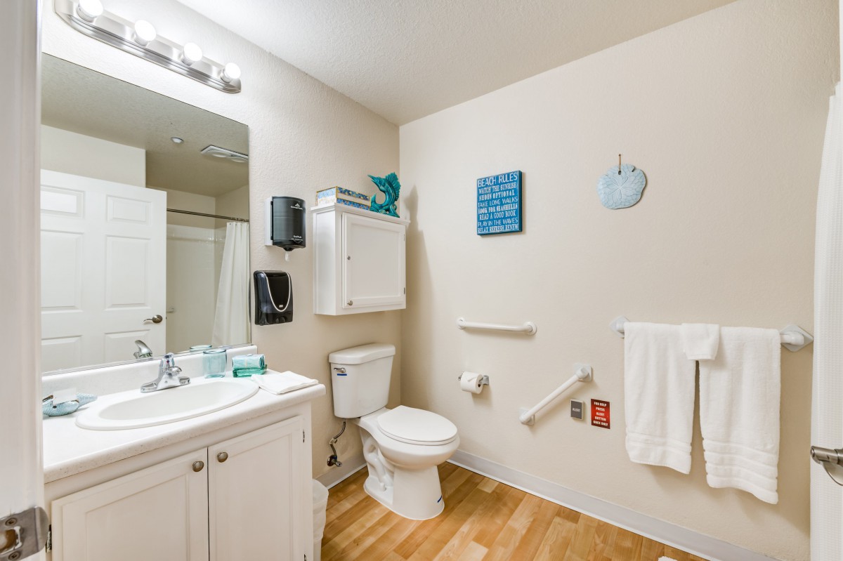 A clean and accessible bathroom equipped with a sink, toilet, and grab bars for safety.