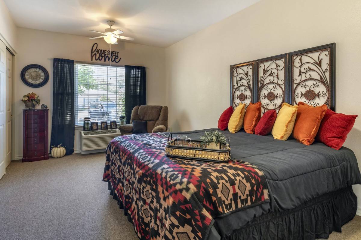 A cozy bedroom featuring a stylish bed with colorful pillows, patterned bedding, and decorative panels as a headboard.