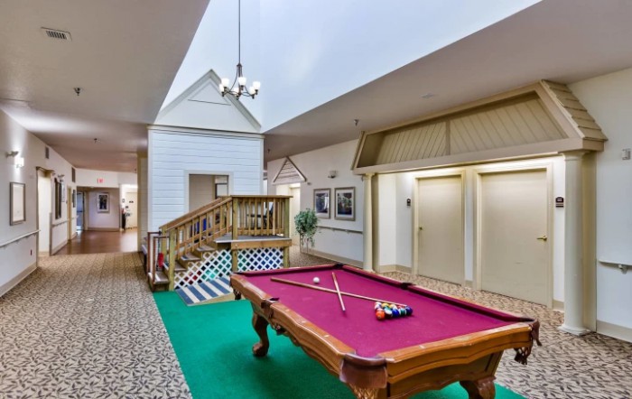 A stylish game room featuring a pool table with a vibrant red cloth, surrounded by decorative interior elements and comfortable lighting.