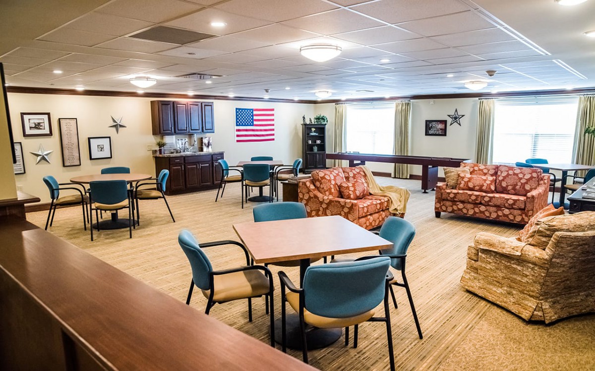 A community recreational room with various seating options and an American flag hanging on the wall.