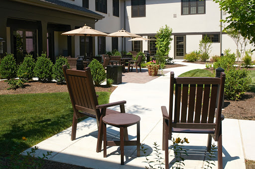 A serene courtyard featuring wooden chairs, patio umbrellas, and well-manicured gardens.