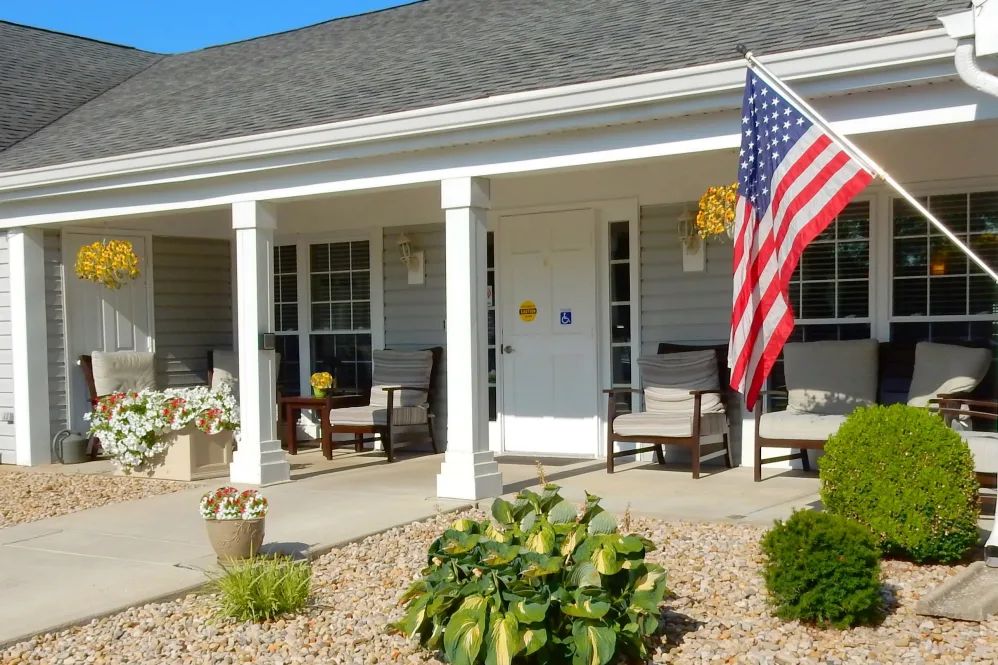 A cozy house porch with chairs and an American flag.