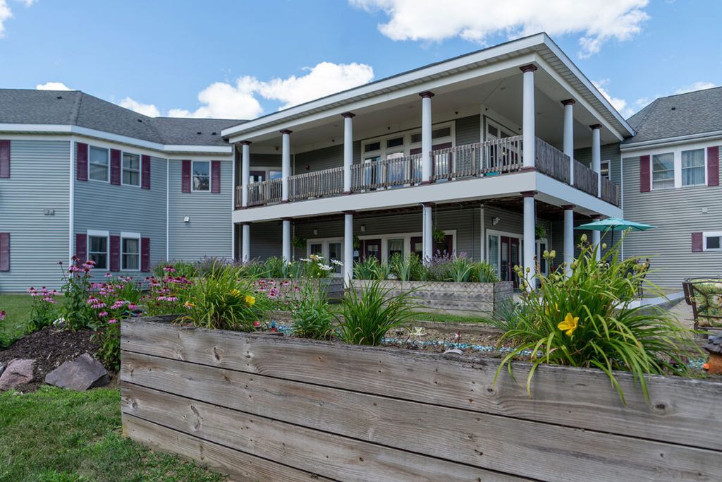A modern two-story house with a landscaped garden and flower beds.
