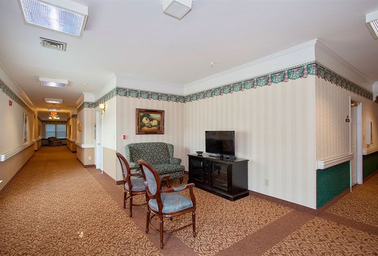 A cozy interior lounge area with a television, chairs, and a sofa next to a corridor.