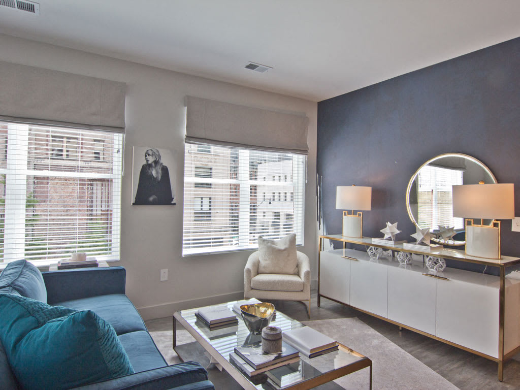 A modern living room with a blue accent wall, featuring a stylish sofa, armchair, and a decorative coffee table.